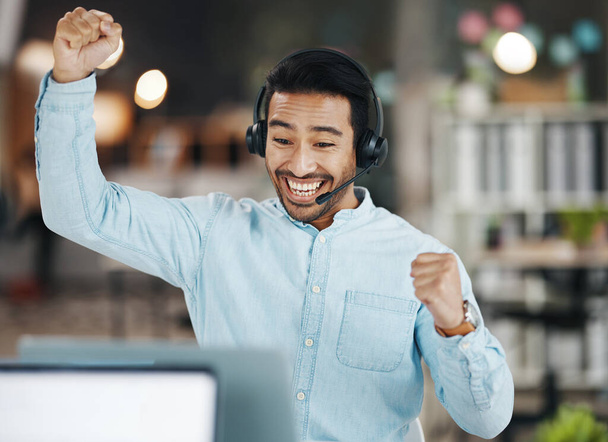 Asian man, call center and celebration for winning, sale or discount on laptop in telemarketing at office. Happy and excited male consultant agent in joy for win, victory or achievement on computer. - Foto, Imagem