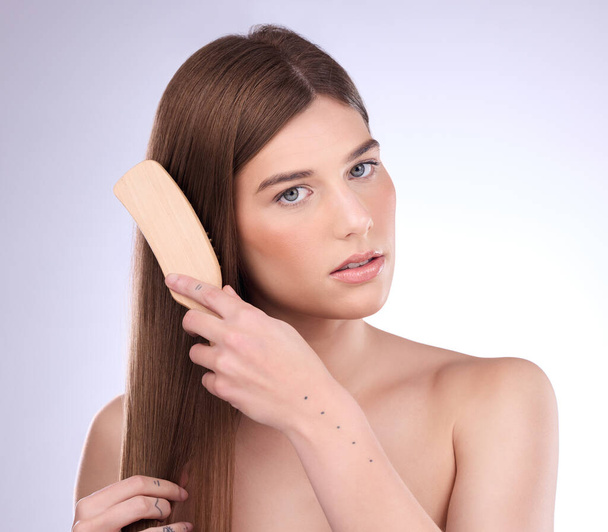 Portrait, beauty and woman brushing hair in studio for for shiny, healthy and growth results on grey background. Face, haircare and brush by girl model relax with luxury comb for smooth care or shine. - Valokuva, kuva