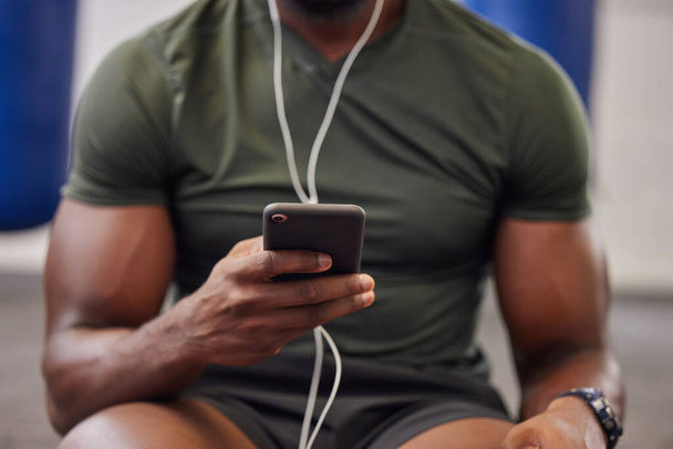 Τηλέφωνο, μουσική και ο άνθρωπος χέρια στο γυμναστήριο για προπόνηση, αναζήτηση social media και online προπόνηση podcast. Closeup αθλητικό πρόσωπο, smartphone και ακρόαση με ακουστικά στο κινητό, εφαρμογή άσκησης και σύνδεση. - Φωτογραφία, εικόνα