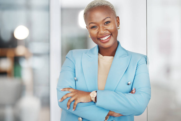Femme noire, sourire portrait et bras croisés dans la gestion de petite entreprise s'appuyant sur le verre dans le bureau moderne. Heureuse femme afro-américaine souriant en toute confiance pour le succès de l'entreprise sur le lieu de travail. - Photo, image