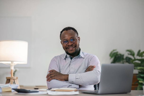 Knappe vrolijke Afro-Amerikaanse uitvoerende zakenman op het kantoor van de werkruimte. - Foto, afbeelding
