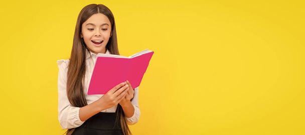 Happy girl child read school textbook yellow background, reading. Horizontal isolated poster of school girl student. Banner header portrait of schoolgirl copy space - 写真・画像
