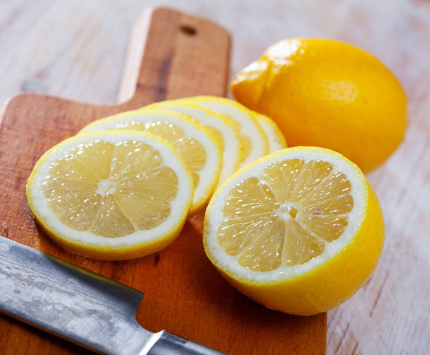Sliced fresh juicy lemon on wooden table. Concept of health benefits of citrus fruits - Photo, image