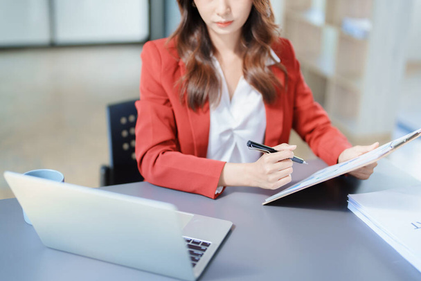 финансовый, планирование, маркетинг и бухгалтерский учет, портрет азиатского сотрудника, проверяющего финансовую отчетность с помощью документов и компьютера на работе.. - Фото, изображение