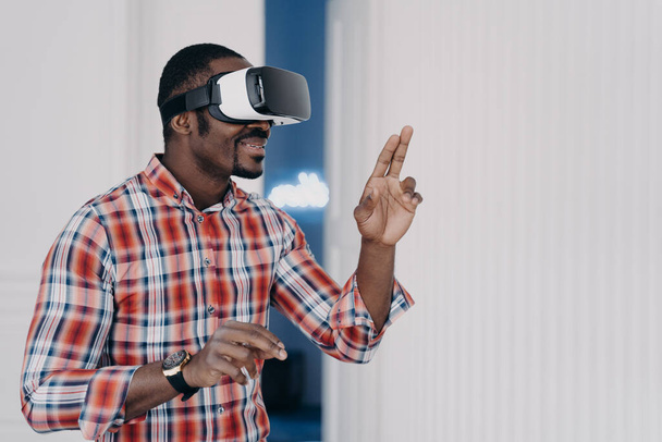 African american guy wearing virtual reality glasses, enjoying leisure free time in cyberspace. Modern black man playing video game simulation, testing purchase in online store. E commerce, tech - Φωτογραφία, εικόνα