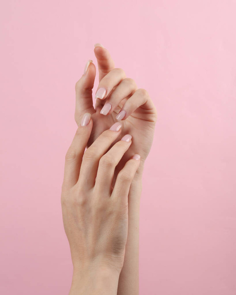 Beautiful female hands with manicure on a pink background. Beauty concept - Fotó, kép