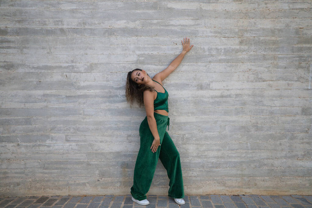 Latin woman, young and beautiful dancing modern dance on a background of gray cement in the street makes different expressions and postures. Concept dance, hip hop, dance, art, action, youth art. - Photo, image