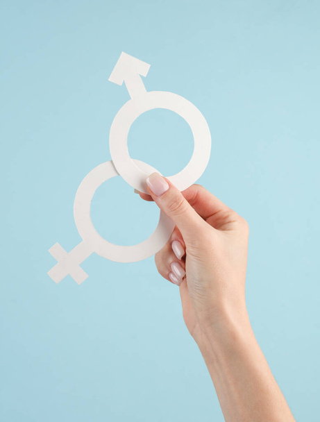Женщины держат в руках мужской и женский гендерный символ на синем фоне - Фото, изображение