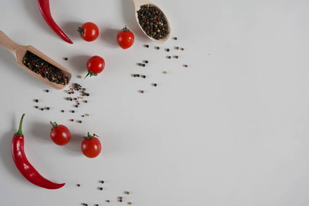 チェリートマト,赤唐辛子ペッパー,白の背景に香り高い黒コショウエンドウ豆.スパイスの背景。フラットレイアウト、トップビュー、コピースペース - 写真・画像