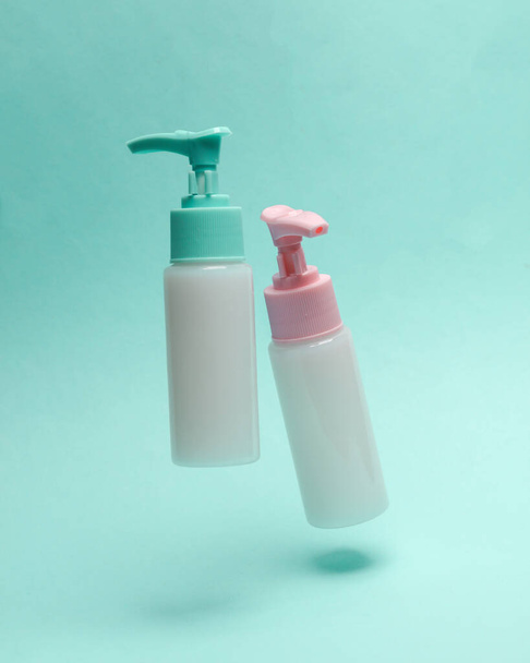 Bottles cream or liquid soap with dispenser levitating on a blue background - 写真・画像