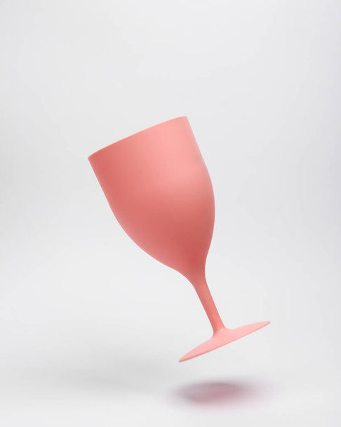 Pink plastic wine glass levitating on white background - Foto, afbeelding