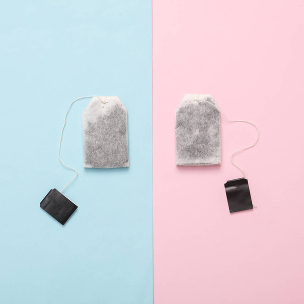 Two tea bags with blank black labels on a pink blue background. Top view - Zdjęcie, obraz
