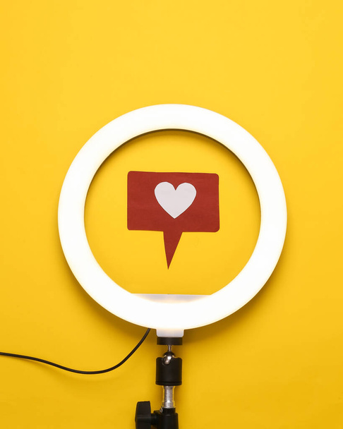 Led ring lamp with smartphone and like icon on yellow background. Blogging and vlogging. Top view - Photo, Image