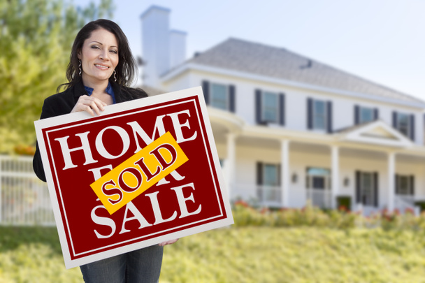 Mujer sosteniendo vendido casa venta signo en frente de la casa
 - Foto, Imagen