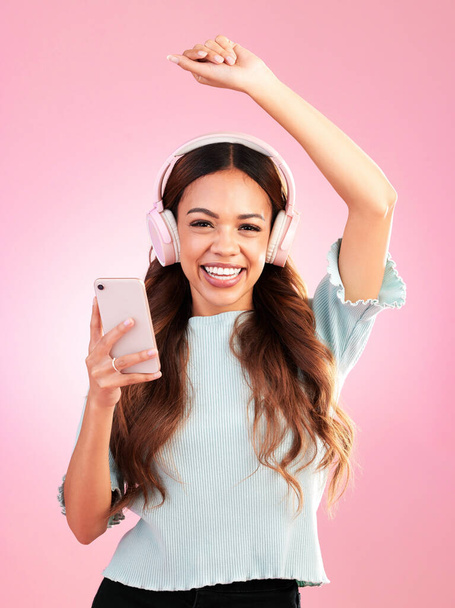 Music headphones, phone and portrait of woman in studio isolated on a pink background. Smile, radio dance and happy female with mobile streaming, enjoying and listening to audio, sound or podcast - Photo, image