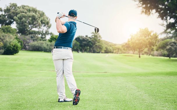Golf, back and hobby with a sports man swinging a club on a field or course for recreation and fun. Golfing, grass and stroke training with a male golfer playing a game on a green during summer. - Foto, afbeelding