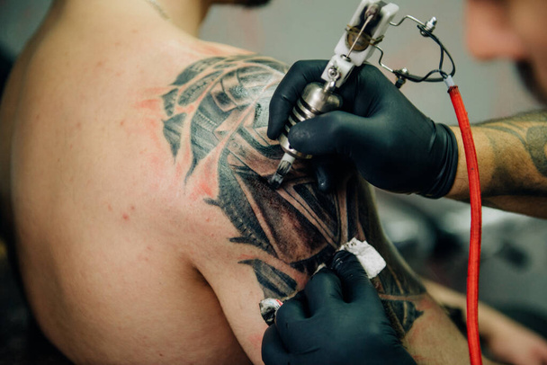 the process of creating a tattoo on the back of a man. Professional tattoo. - Foto, Imagen