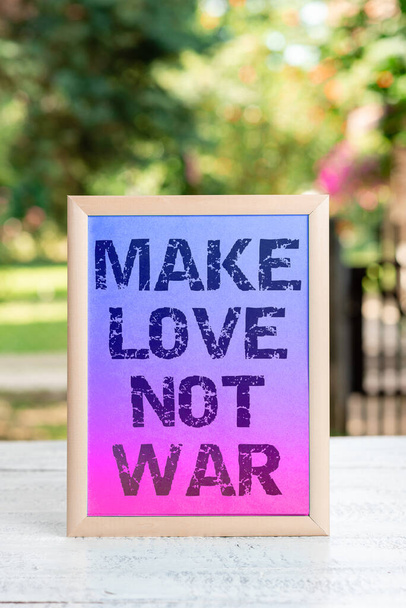 Texto de escritura a mano Make Love Not War, escaparate de negocios Un eslogan hippie contra la guerra que alienta el amor y la paz - Foto, imagen