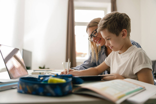 Happy mom and son doing homework and studying with laptop together. High quality photo - Photo, Image