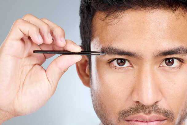 I like to keep things neat and tidy. a handsome man tweezing his eyebrows - Foto, afbeelding