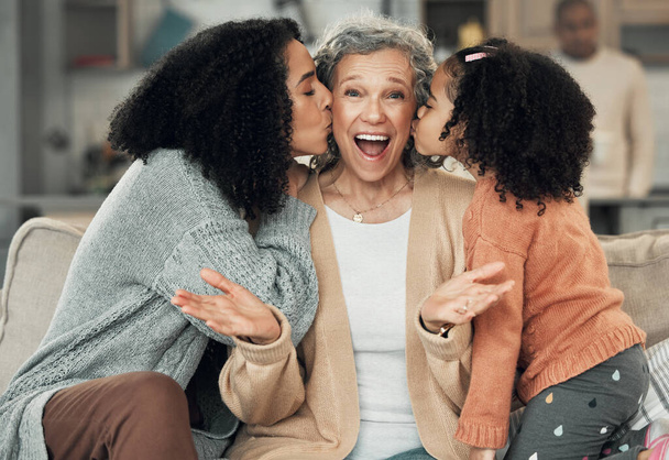 Portrait, kiss and grandmother with girl and woman on a sofa, smile and happy at family home together. Kissing, face and excited senior with adult daughter and grandchild on couch, bond and joy. - Photo, Image