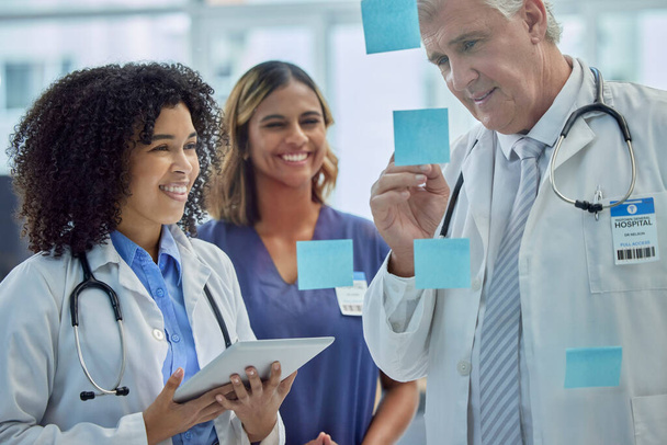 Planning, training and doctors teamwork on glass board for healthcare management and internship workflow on sticky note. Medical students, people or woman with manager writing ideas for clinic goals. - Photo, Image