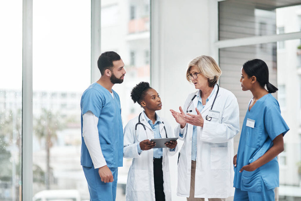 Crear un plan ejecutable para sus pacientes. un grupo de médicos que tienen una discusión en un hospital - Foto, Imagen