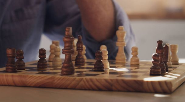 Pidämme aivomme aktiivisina shakkipelillä. tunnistamaton mies istuu yksin ja pelaa shakkia kotona keittiössä - Valokuva, kuva