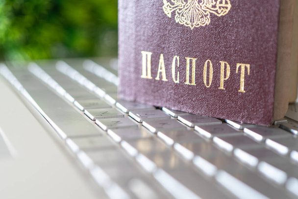 Az Orosz Föderáció útlevele egy szürke laptop billentyűzeten. A felhasználó azonosítása az interneten. Útlevéladatok nélküli internet-hozzáférés tilalma. - Fotó, kép