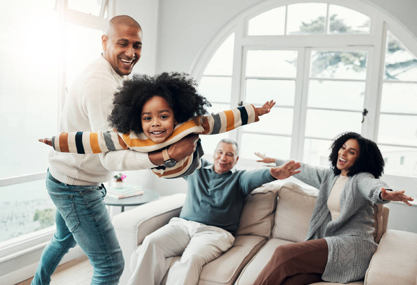 Airplane, father and girl in lounge, family an playing with love, quality time and cheerful together. Portrait, happy dad lifting daughter and granddad with mother, joyful and games in living room. - Photo, image