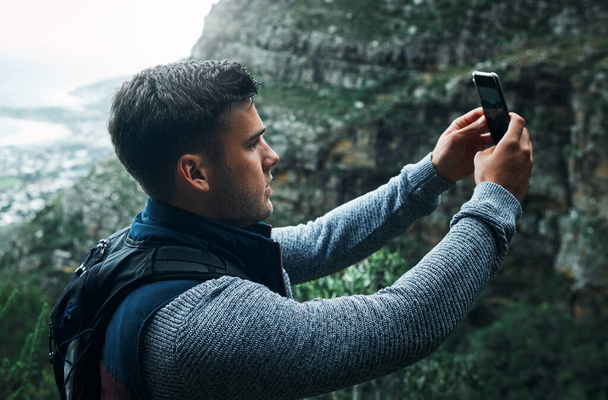 Snapping the moment. a young man taking selfies while out on a hike - Fotoğraf, Görsel