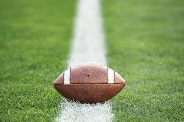 close up view of an American Football sitting on a grass football field on the yard line. Generic Sports image - Photo, Image