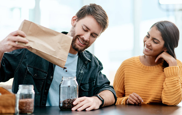 Reduzca el riesgo al hacer recados. una pareja joven empacando sus comestibles en recipientes de vidrio después de regresar a casa de la tienda - Foto, Imagen