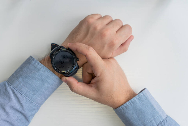 bedrijfs-, technologie- en mensenconcept. close-up van mannelijke handen zetten slimme horloge. bovenaanzicht - Foto, afbeelding