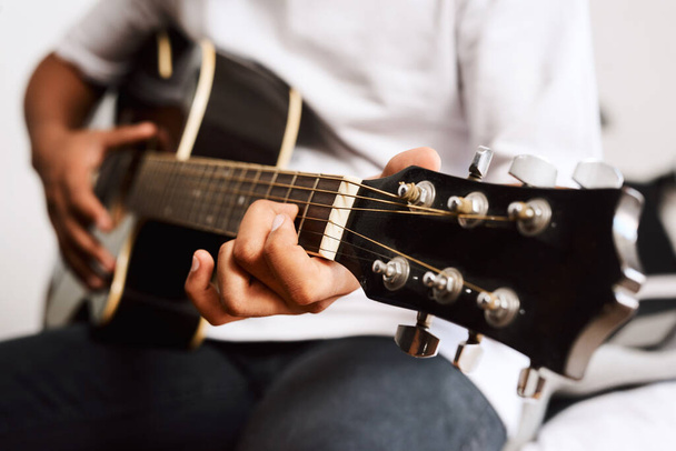 Usa tu tiempo libre para aprender algo nuevo. un joven tocando la guitarra mientras está sentado en casa - Foto, Imagen