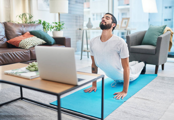 Bu çevrimiçi dersler her seviyede fitness için. Evde yoga yaparken laptopunu kullanan bir adam. - Fotoğraf, Görsel