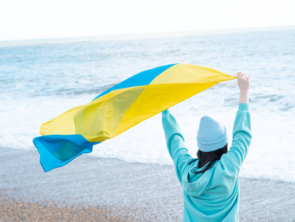 brunnete kobieta w niebieskiej bluzie z kapturem i niebieski kapelusz z flagą narodową Ukrainy, patriotyczne pojęcie - Zdjęcie, obraz