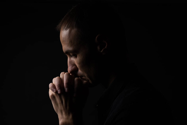 Portrait of a handsome man praying over gray background. - Photo, Image