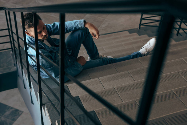 Upset man sitting on stairs indoors. Loneliness concept - Valokuva, kuva