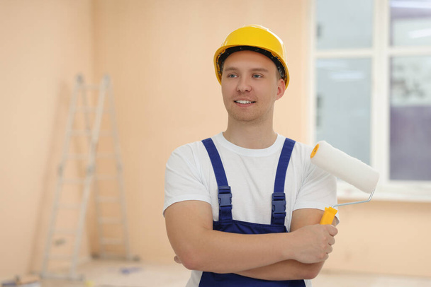 Worker holding paint roller in unfinished room. Space for text - Foto, Imagem