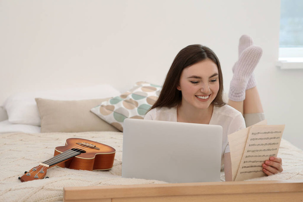 Woman learning to play ukulele with online music course at home. Space for text - Photo, image