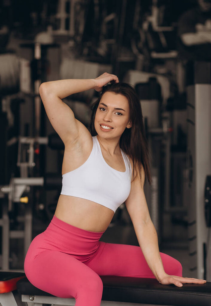 a beautiful girl in the gym sits on a bench - Foto, afbeelding