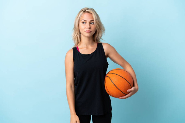 若いですロシア人女性プレイバスケットボール孤立しました上の青の背景に疑問を持っています - 写真・画像