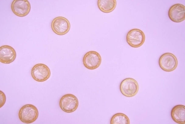 Many white packages of unopened condoms on a pink background. The concept of safe sex and reproductive health. - 写真・画像