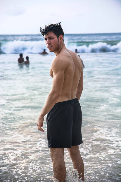 Handsome young man standing on a beach in Phuket Island, Thailand, shirtless wearing boxer shorts, showing muscular fit body - Foto, Imagem