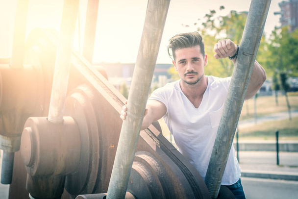 Attractive man in urban setting in front of big metal structure - Foto, immagini
