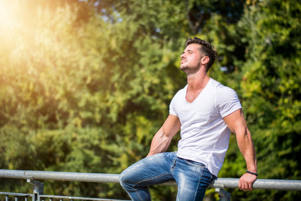 Attractive muscular man in city park in a nice summer day - Photo, Image