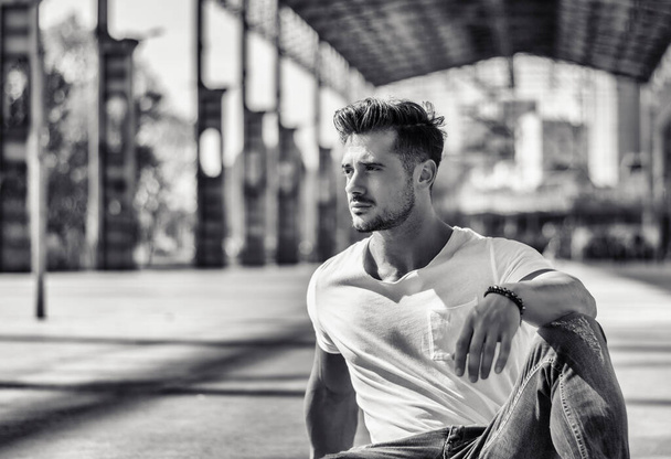 Attractive man in urban setting under big metal structure, a former industrial site - 写真・画像