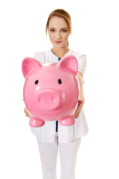 Female doctor holding a piggybank. - Foto, immagini