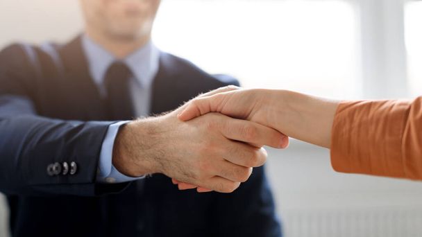 Business partnership. Male and female entrepreneurs shaking hands, celebrating cooperation agreement at office, cropped, closeup. Businessman and businesswoman handshaking after successful deal - Photo, Image